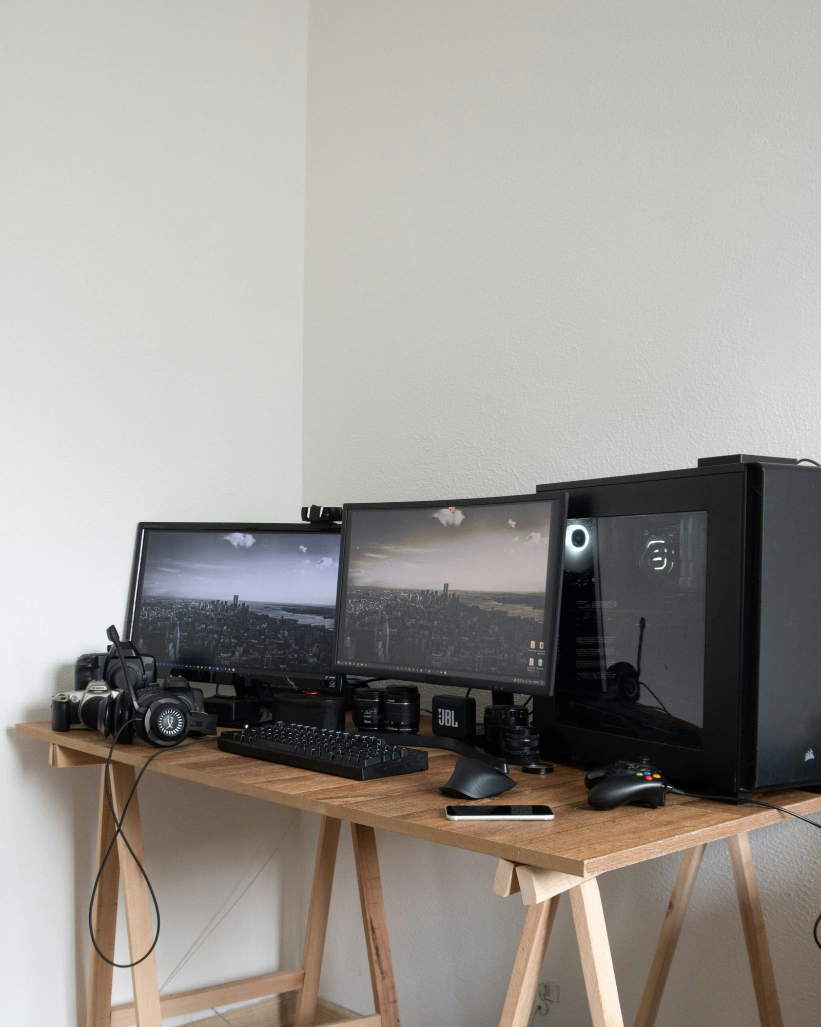 Desktop of modern photographer with computer screens and modern devices among camera lenses in light room at home